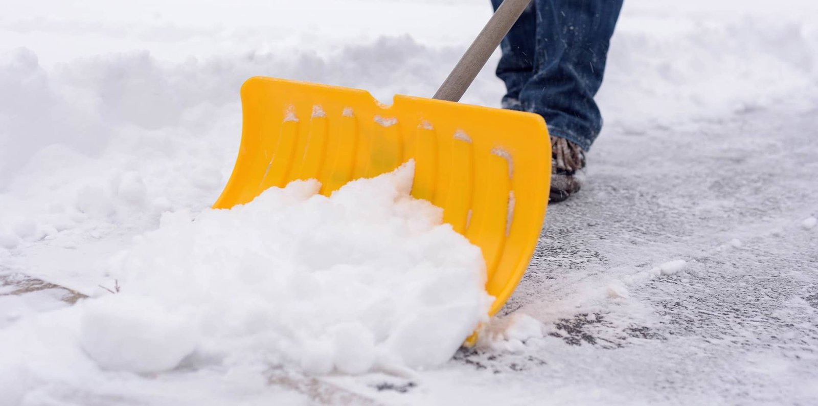 Ein Mitglied des Winterdienstes von BR-Montage entfernt Schnee mit einer Schaufel von einem Gehweg, um die Sicherheit im Winter zu gewährleisten.